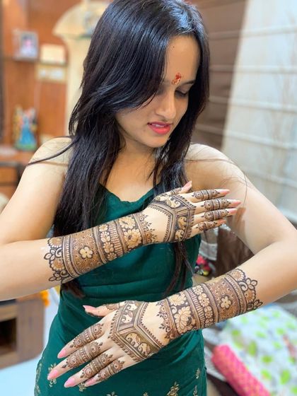 A client admiring her engagement mehndi. The design features beautiful floral bands and elephant motifs, symbols of good luck and happiness.