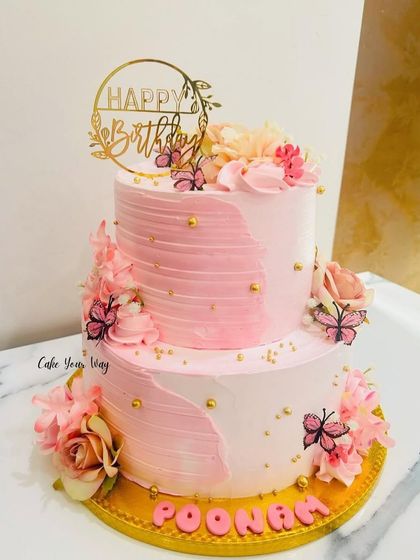 A cake so pretty, it deserves a solo photoshoot. This two-tier pink ombre cake is decorated with flowers and butterflies for an elegant look.