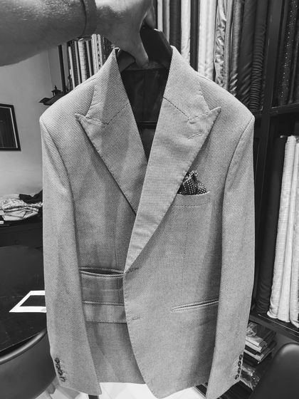 A behind-the-scenes look at a light grey suit jacket in my studio. You can see the sharp peak lapels and structured shoulders that are hallmarks of my tailoring.