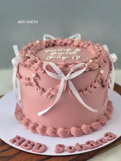 I have a soft spot for vintage-style cakes. This design features intricate piping work and delicate ribbon bows on a dusty rose whipped cream base. It’s a 17th birthday cake in my popular Chocolate Mousse flavour, showing that elegance can be timeless and sweet.