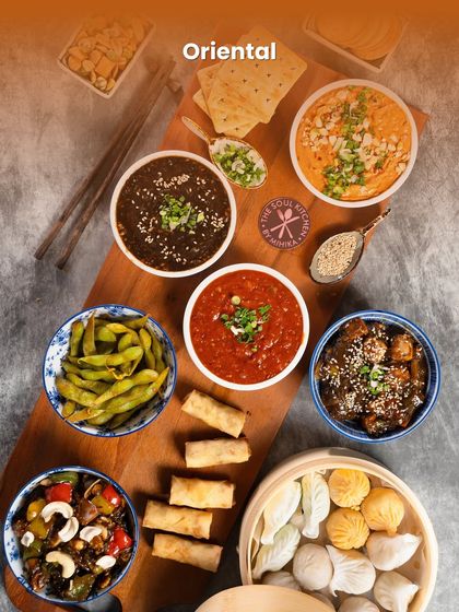 An abundant Oriental platter featuring dimsums, spring rolls, and flavourful sauces for a Pan-Asian themed party.