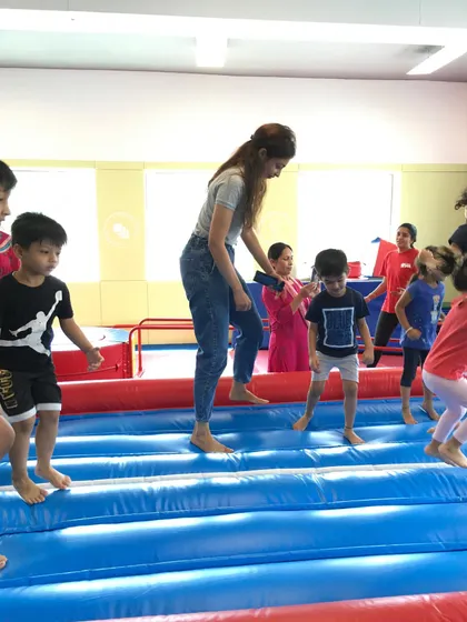 More fun on the tumble track. A parent helps a child jump, highlighting the interactive and family-friendly nature of our special events and camps.
