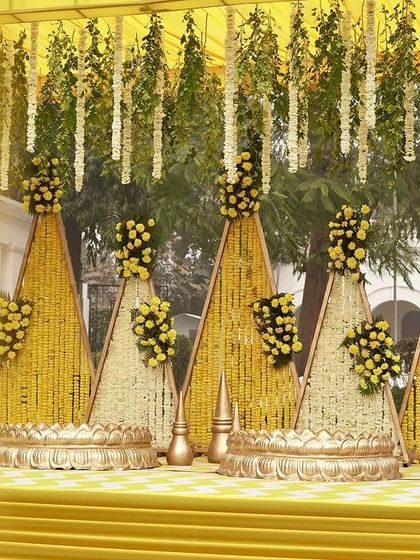 A detailed view of the traditional yellow Haldi stage, adorned with cones of marigolds and hanging floral strings.