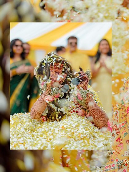 An artistic shot of the bride amidst a shower of petals, her hands framing her face in a moment of pure joy.
