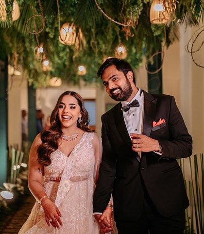 The happy couple making their entrance at the 'Retro Jungle' sangeet. The passage was lined with foliage and hanging lights, creating a fun and dramatic entry for the night's stars.