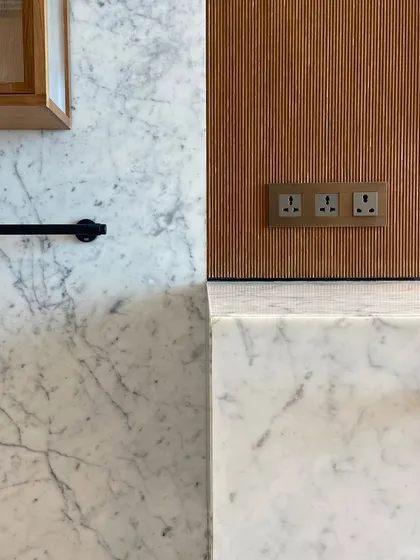 A composition of materials in one of the Worli Duplex bathrooms. Carrara marble, fluted wood, and black metal fixtures come together to create a palette that is both timeless and contemporary.