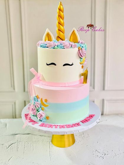 A dreamy two-tier unicorn cake for a first birthday. This cake features a golden horn, cute ears, and a pastel rainbow design, making it a magical centerpiece for a little one's special day.