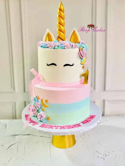 A dreamy unicorn delight to celebrate a big first birthday. This two-tier cake features pastel rainbow stripes on the bottom and a cute unicorn face on top, complete with a golden horn.