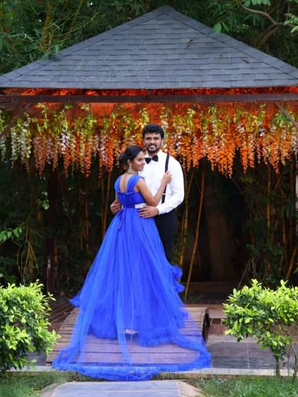 A romantic photo of a couple under a canopy of flowers. The trail of the blue ball gown adds a touch of elegance to this beautiful garden setting.