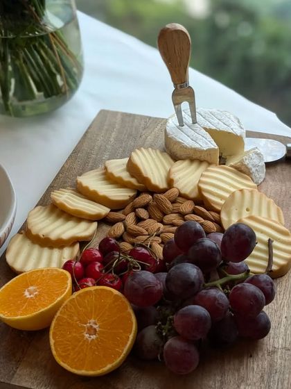 A simple and fresh platter with a wheel of brie, crunchy almonds, sweet grapes, and citrus slices. It’s a perfect, light accompaniment for any social gathering.