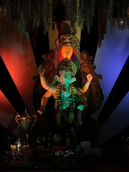 The Palmbeach Cha Vighnaharta idol under dramatic red and blue lighting, showcasing the creative use of light in modern pandals.