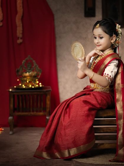 Her eyes hold all the beauty of the world. A little girl in a traditional saree admires herself in a brass mirror.