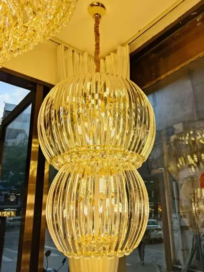 This two-tiered chandelier features vertical crystal rods that create a beautiful, ribbed texture. The warm, golden light filters through the crystals, producing a sophisticated glow ideal for a luxurious living or dining room.