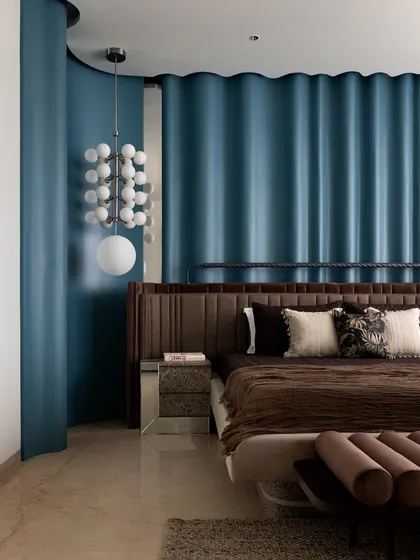 The master bedroom, where the deep blue ripple wall creates a dramatic and luxurious backdrop for the custom bed and statement lighting.
