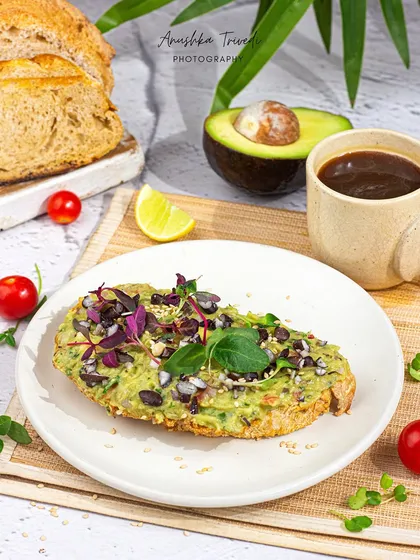 A slightly different angle of the avocado toast, showing more of the fresh ingredients and the bright, sunny setting.