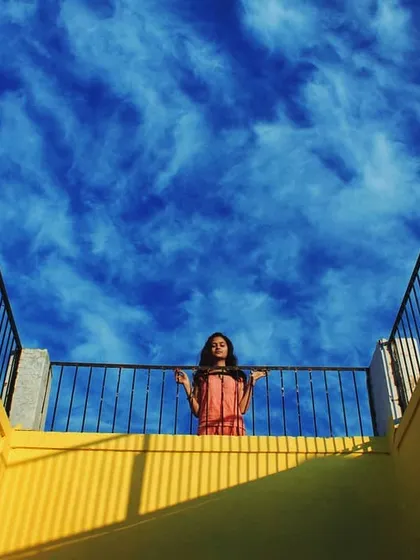Looking up from below, I framed this shot to capture the dramatic contrast between the bright yellow architecture and the deep blue, cloud-filled sky. The person on the balcony becomes a small but significant part of a grand, geometric composition.