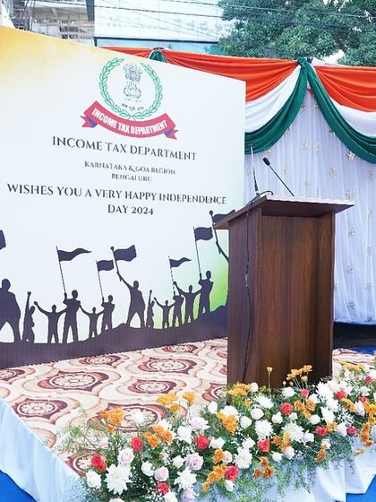 The podium and backdrop setup for the Independence Day event. We provide a formal stage for speeches and official proceedings, complete with floral decor and branded backdrops.