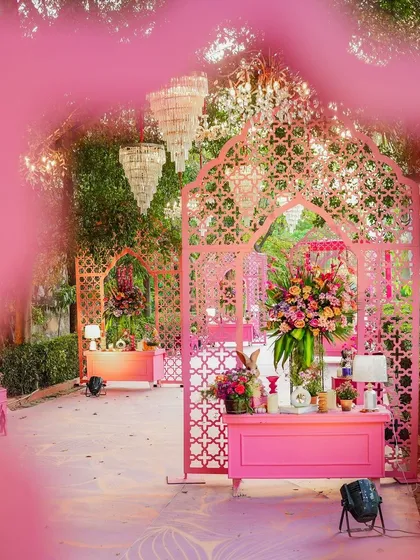 A dreamy perspective of the pink-themed Mehendi setup. The layered arches and hanging chandeliers create a sense of depth and enchantment, making the space feel like a modern fairytale.