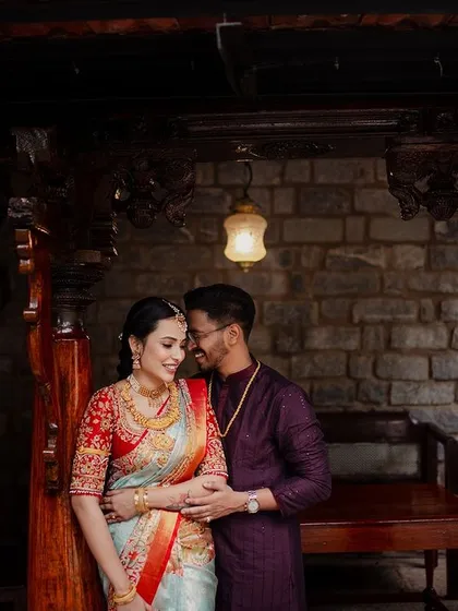 An intimate portrait of a couple, framed by the carved wooden pillars of a traditional seating area.