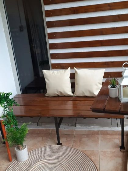 Another angle of the polished pinewood balcony, showing how the different elements work together. The round jute rug on the tiled floor adds another layer of texture to the design.