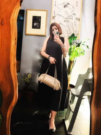 A mirror selfie capturing a simple yet elegant look. A classic black sleeveless midi dress is a wardrobe staple that always looks chic and put-together.