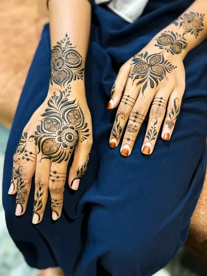 A simple yet elegant Arabic henna design. This style is perfect for bridesmaids or guests, with bold floral motifs on the back of the hand and delicate patterns on the fingers.