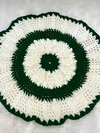 A flat-lay of the green and white table mat, showing the circular pattern and textured stitches.
