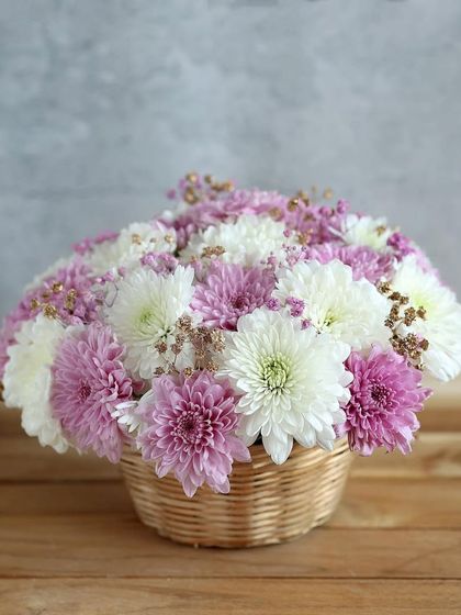 A simple and sweet basket of purple and white chrysanthemums, a charming and rustic floral gift.