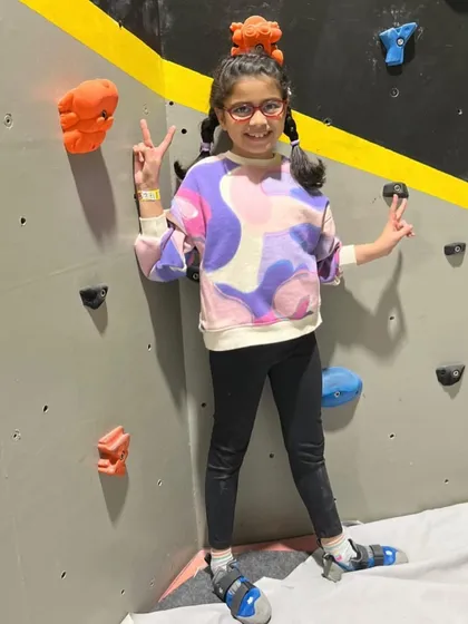 Peace, love, and climbing. This young climber is all geared up and ready to take on the wall, showing off her cool moves and even cooler attitude.