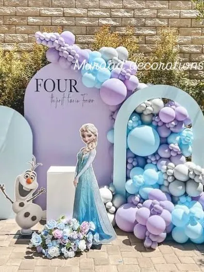 We took the magic of Frozen outdoors for this fourth birthday party. The setup includes character cutouts of Elsa and Olaf against beautiful arched backdrops and a stunning balloon arrangement in icy blue, purple, and silver.