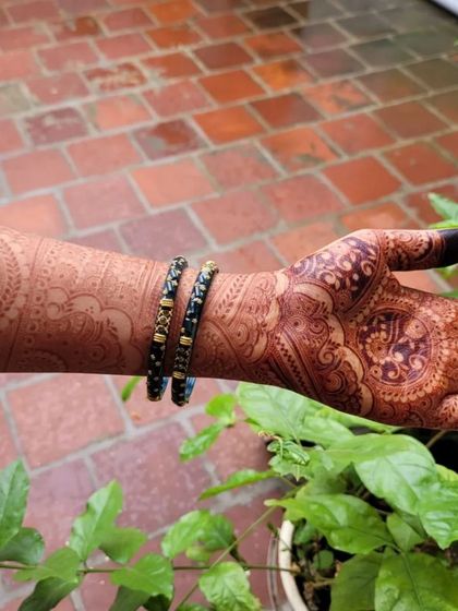A look at a fully completed bridal henna design with eye-catching mandalas and flowing patterns. The dark fingertips and detailed work create a classic and rich look for any bride.