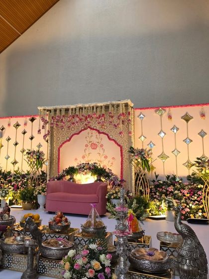 A stage setup with a pink floral backdrop and modern mirrored panels.