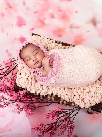 A beautiful overhead shot of a newborn sleeping peacefully, surrounded by delicate pink blossoms. This artistic composition creates a stunning and memorable image.