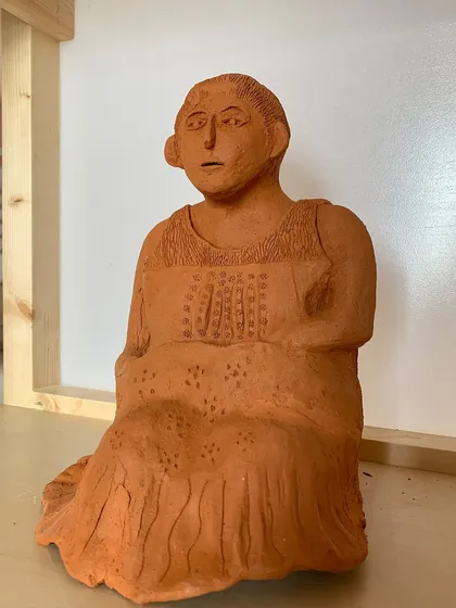 A front view of the terracotta sculpture, showing the detailed texture of the dress and the figure's serene expression.