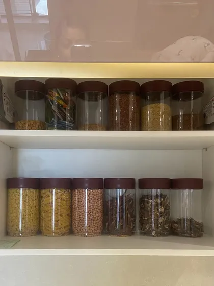 A pantry cabinet filled with pasta, lentils, and whole spices. By taking items out of their bulky packaging, we create more space and a much cleaner look.