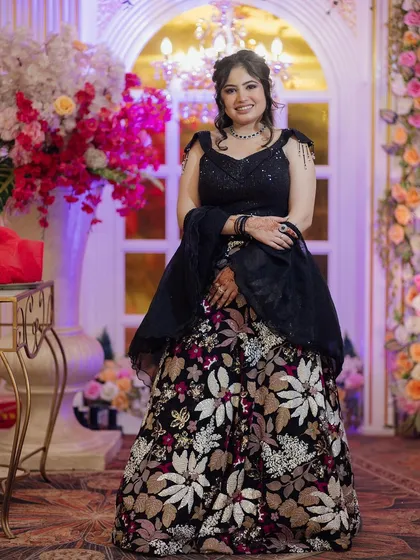 A happy client in the black floral rental lehenga. The combination of a dark base with colorful floral work makes it a unique and memorable outfit.