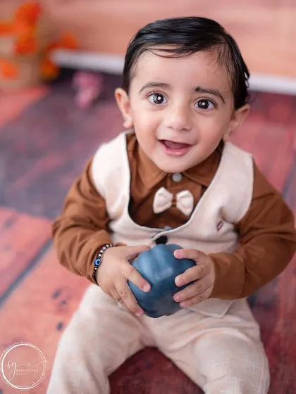 A close-up shot capturing a bright, happy smile and the details of his adorable formal outfit.