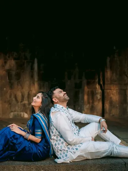 Sitting back-to-back, the couple looks up as if dreaming of their future together. The dark archway creates a dramatic frame, highlighting their profiles.
