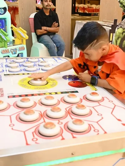 A young guest in his superhero cape tests his reflexes at the light-up reaction game. It's important to have a mix of both creative and active games.