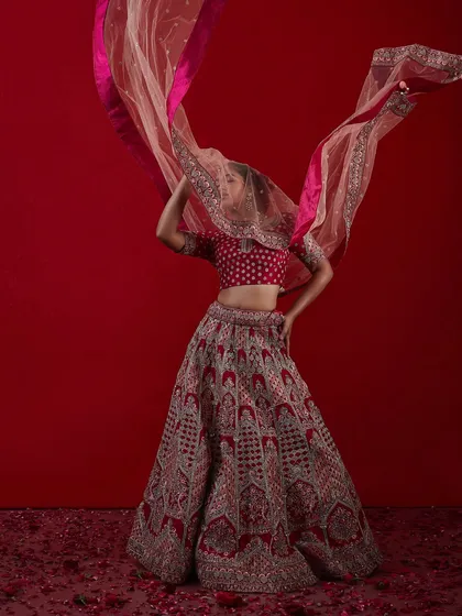 A dynamic shot of a bride with a flowing pink and red dupatta, showcasing a modern and vibrant bridal style.