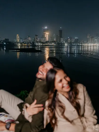 A soft-focus, dreamy shot of a couple sharing a laugh against the glittering Mumbai skyline at night. This image captures the vibrant, romantic energy of the city after dark.