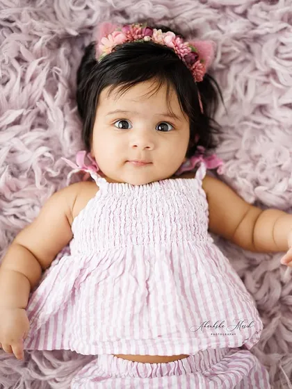 A full-body shot of this baby girl in her cute striped outfit. This pose shows off her sweet personality and the adorable details of her attire.