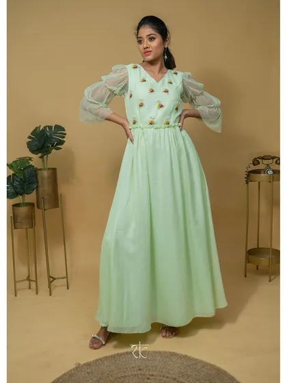 This floor-length georgette dress in a serene teal green is the essence of understated elegance. The design focuses on a graceful silhouette, with delicate threadwork and unique puffed net sleeves for a touch of romance.