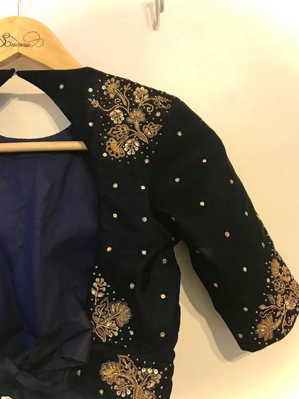 A view of the shoulder and sleeve of a black velvet blouse, adorned with scattered sequins and floral zardosi embroidery.