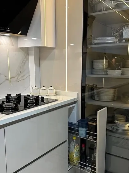 Functionality in detail: this image shows a pull-out spice rack next to the hob and a tall, glass-fronted pantry unit. The design ensures that all cooking essentials are organized and easily accessible.