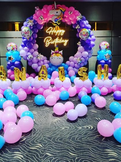 A wide shot of the unicorn birthday party decor, showcasing the impressive scale of the balloon arch and the scattered balloons on the floor.