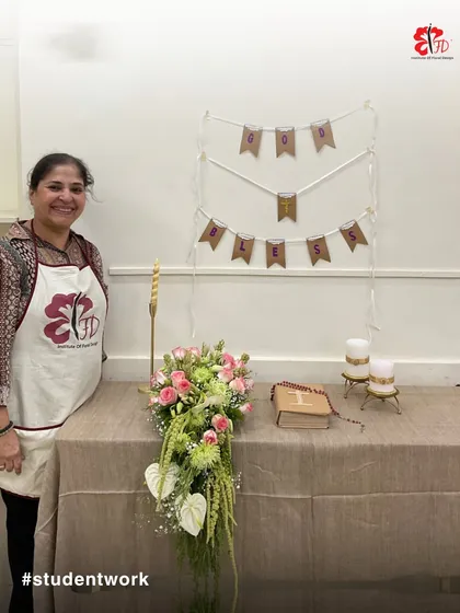 A student proudly stands by her elegant Holy Communion arrangement. This project teaches how to create a themed display with a cascading bouquet, candles, and other symbolic elements.