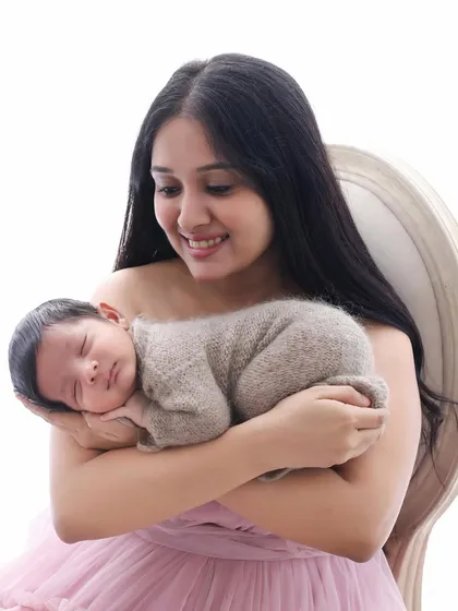 A smile that says it all. This close-up captures a new mother's joy as she holds her sleeping baby. These are the quiet, heartfelt moments I strive to preserve.