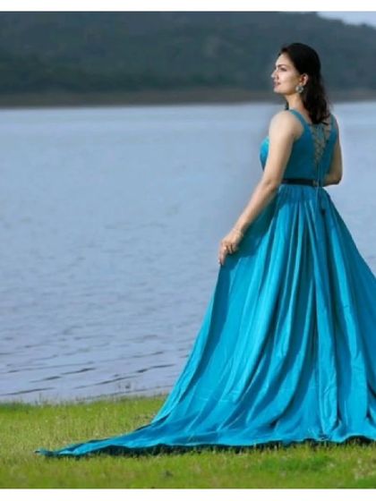 A beautiful shot of our teal blue gown with a long trail, perfect for a pre-wedding shoot by the water. The color looks stunning against the natural scenery.