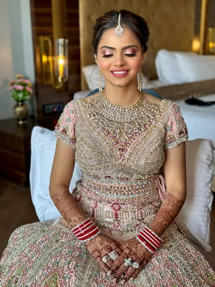 A beautiful smiling shot of the bride. Her eyes are closed, showcasing the soft, blended pink eyeshadow, while her skin glows with a healthy, dewy finish.
